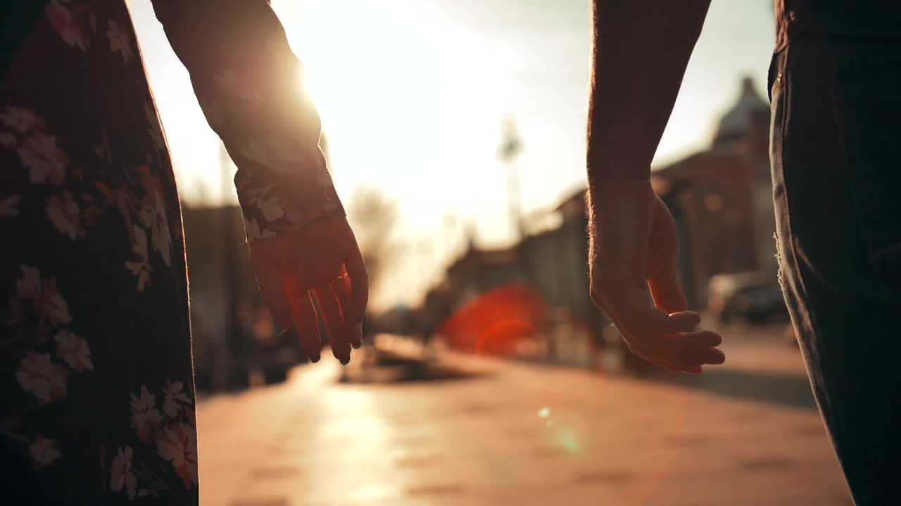 A symbolic close-up of two hands, a couple walking at sunset, evoking themes of connection, relationship growth, and couples therapy.